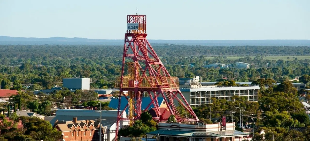 A tall red steel mining headframe rising above the town of Kalgoorlie, home of the Museum of the Goldfields