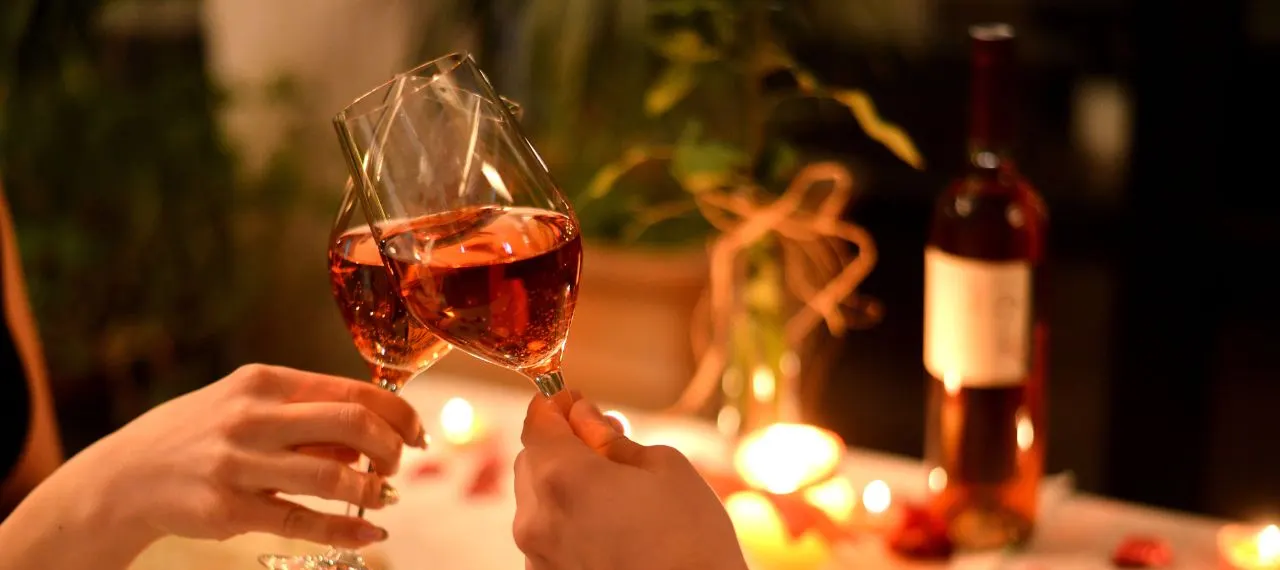 Two people raising glasses of Great Southern wine by candlelight